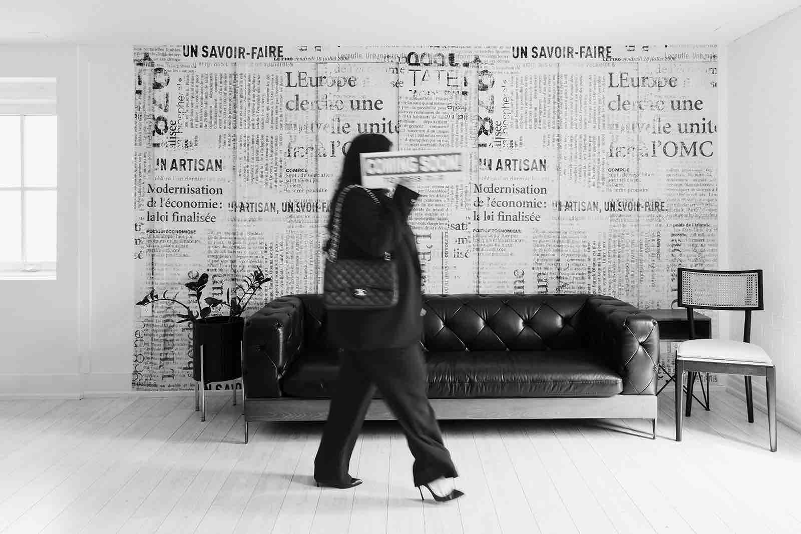 Kaylin Smith carrying a Coming Soon listing sign through a bright office.